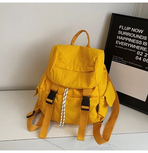 Detailed view of casual yellow nylon backpack with buckle straps and striped drawstrings