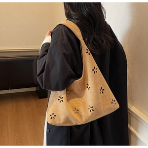 Close-up of laser-cut floral patterns on tan suede shoulder bag for women