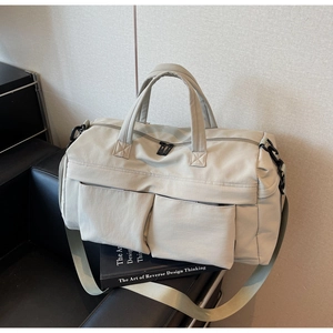 Detail of grey travel bag with dual front pockets and adjustable wide shoulder strap
