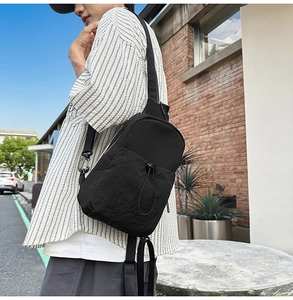 Detailed view of a black waterproof nylon crossbody chest bag worn by a person outdoors