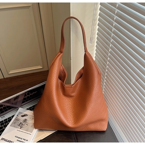Close-up of large brown lychee grain hobo shoulder bag in a modern office setting