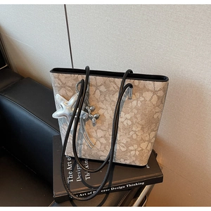Detail view of floral print tote bag with leather straps and starfish charm accessory