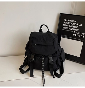 Detail of black waterproof nylon backpack featuring dual buckles and drawstring closure