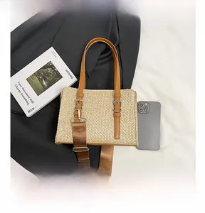 Detailed top view of a straw woven crossbody bag with brown leather straps and accessories