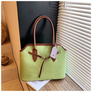 Close-up of olive green suede tote bag with brown leather accents and silver buckle detail