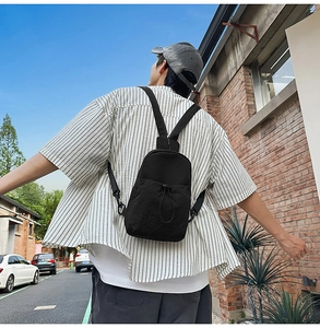 Detail of lightweight black nylon sling bag with drawstring pocket in urban setting
