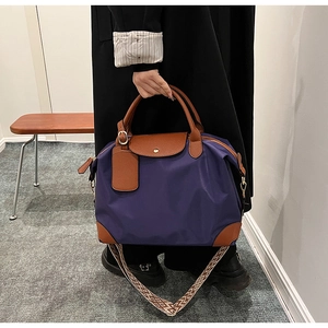 Detail of purple nylon tote bag with brown leather handles and geometric woven shoulder strap