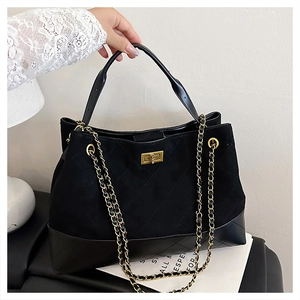 Detail of black quilted suede and leather tote with gold metal turn-lock and chain strap