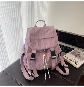 Close-up of purple nylon backpack with flap closure and buckle details on a desk