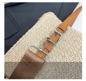 Detail of silver metal hook and leather strap on a woven straw beach bag
