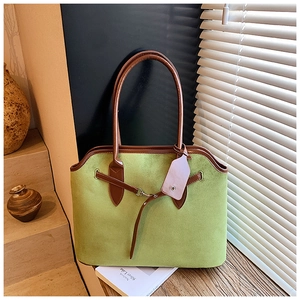 Close-up of green faux suede tote bag with brown leather straps and metal buckle detail
