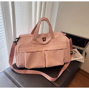 Detailed close-up of pink travel bag with front pockets and adjustable shoulder strap