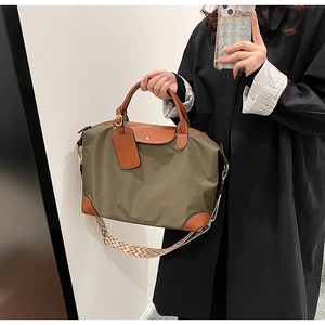 Detail of olive nylon tote with brown leather handles and geometric woven shoulder strap
