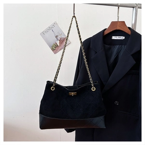 Close-up of black quilted suede tote with gold chain strap and square metal turn-lock