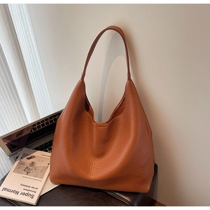 Close-up of brown litchi pattern leather tote bag with wide shoulder strap