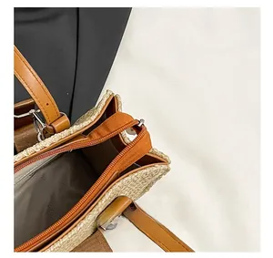 Detail view of woven straw bag showing zip closure and gray herringbone lining