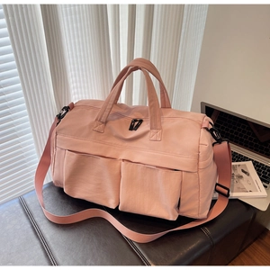 Detail of light pink travel duffel bag with dual handles and adjustable shoulder strap