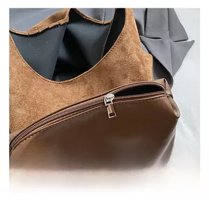 Detailed close-up of smooth brown faux leather texture and silver metal zipper on tote bag