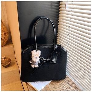 Close-up of black suede tote bag texture with cute puppy pendant on wooden table