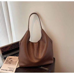 Detail of dark brown pebble leather tote bag featuring rich texture and hobo style shape