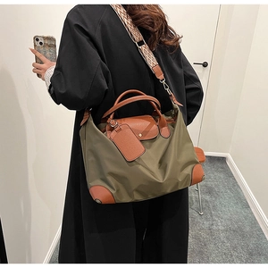 Olive nylon tote bag with brown leather details and geometric strap worn by model