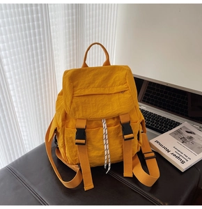 Macro detail of vibrant yellow nylon backpack with buckle closure on a dark setting