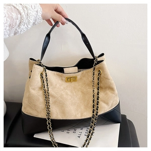 Detail of quilted beige suede and black leather bag with gold twist lock and chain strap