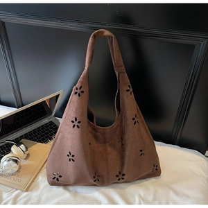 Detail of a brown suede tote bag featuring floral laser-cut patterns and a soft texture