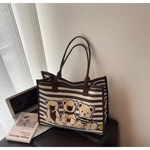 Détail du sac cabas en toile rayée avec broderie d'ours en peluche et ordinateur portable chic