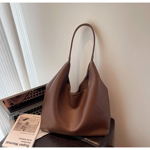 Deep brown large tote bag with lychee texture leather on a minimalist laptop background