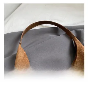 Detailed close-up of brown suede tote bag handle with high-quality stitching and smooth texture
