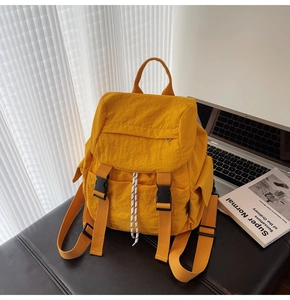 Detail of yellow nylon backpack featuring buckle closures and adjustable shoulder straps