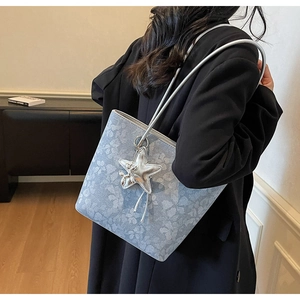 Detail of light blue floral tote bag with large silver star charm on black suit