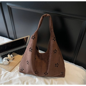 Detail of dark brown faux suede tote bag featuring intricate laser-cut floral patterns