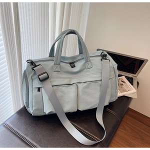 Detail view of large light blue travel bag with reinforced handles and front snap pockets