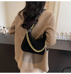 Detail of black suede hobo bag featuring chunky gold chain and leather shoulder strap
