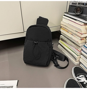 Detail of black nylon chest bag with drawstring pocket and adjustable shoulder strap