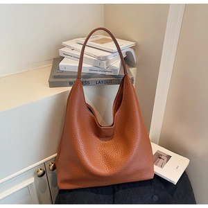 Detail of orange-brown pebble leather tote bag with soft texture and wide shoulder strap