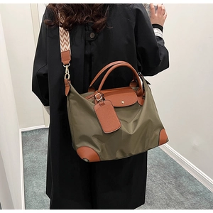 Detail of olive green nylon tote with brown leather handles and chevron crossbody strap