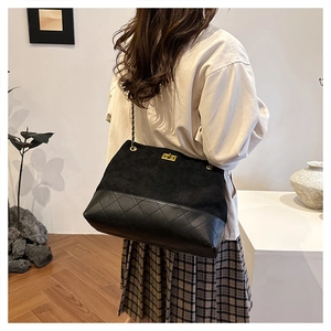 Macro detail of black suede and quilted leather tote with golden chain strap