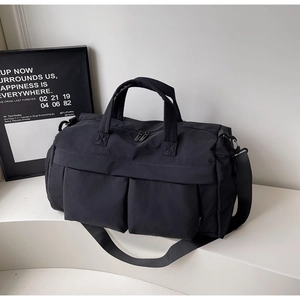 Macro detail of black nylon travel bag with dual front pockets and adjustable shoulder strap