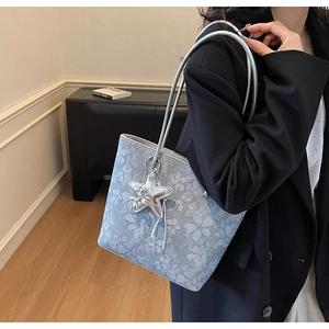 Detail of floral print tote bag with silver star charm and metallic animal ornament