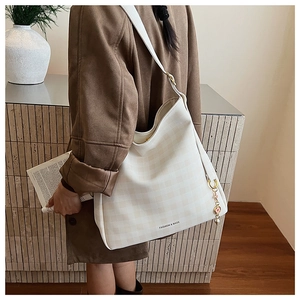 Dettaglio di una grande borsa tote crema a scacchi con ciondolo rosa e charm di perle