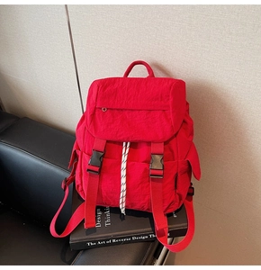 Detail of red nylon backpack showing drawstring closure and buckle flap design