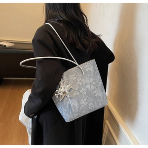 Detail of gray floral tote bag featuring a silver star charm and elegant print