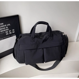 Detail of black multi-functional travel bag featuring front pockets and adjustable strap