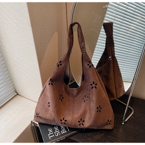 Close-up of dark brown suede tote featuring laser-cut floral patterns and texture