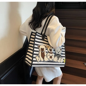 Détail du grand sac cabas en toile rayée avec patchs ours porté par un mannequin