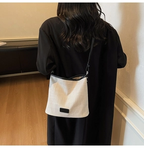 Dettaglio della borsa a secchiello in tela con finiture in pelle nera e logo sobrio