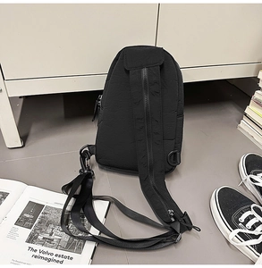 Detail of a black nylon chest bag showing the adjustable zippered shoulder strap and D-ring